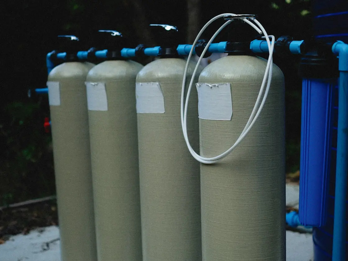 Fiberglass water treatment tanks with control valves and a blue filter housing