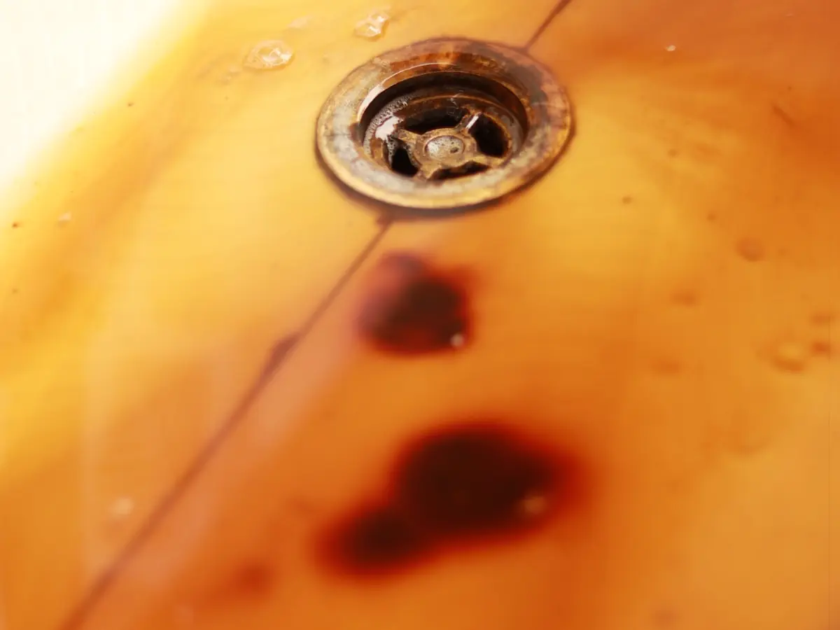 Orange and brown iron staining running down a bath towards the drain