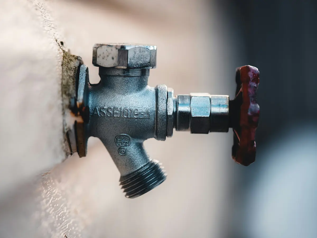 An outdoor hose bib faucet mounted on a house wall
