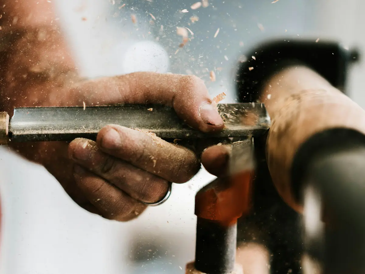 Hands cutting a length of metal pipe with sparks flying