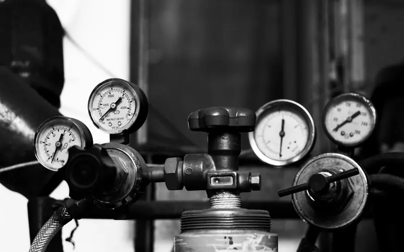 Pressure gauges and valves on a water line, in black and white