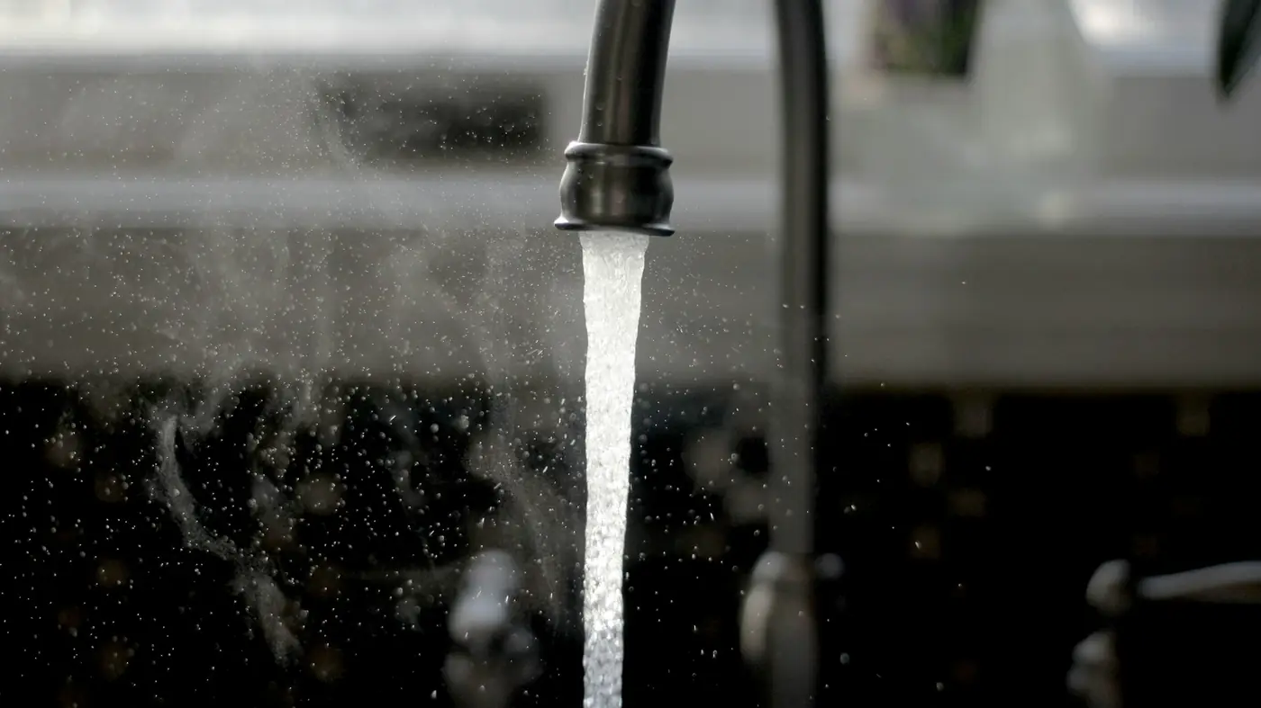 Water running from a black kitchen faucet into a sink