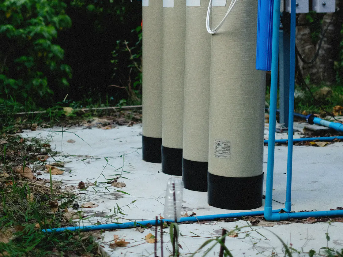 Fiberglass water treatment tanks plumbed together with blue pipe outdoors