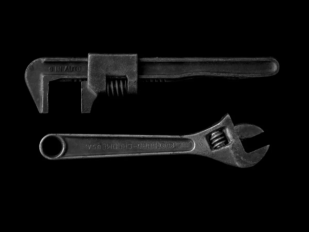 A pipe wrench and an adjustable wrench on a black background